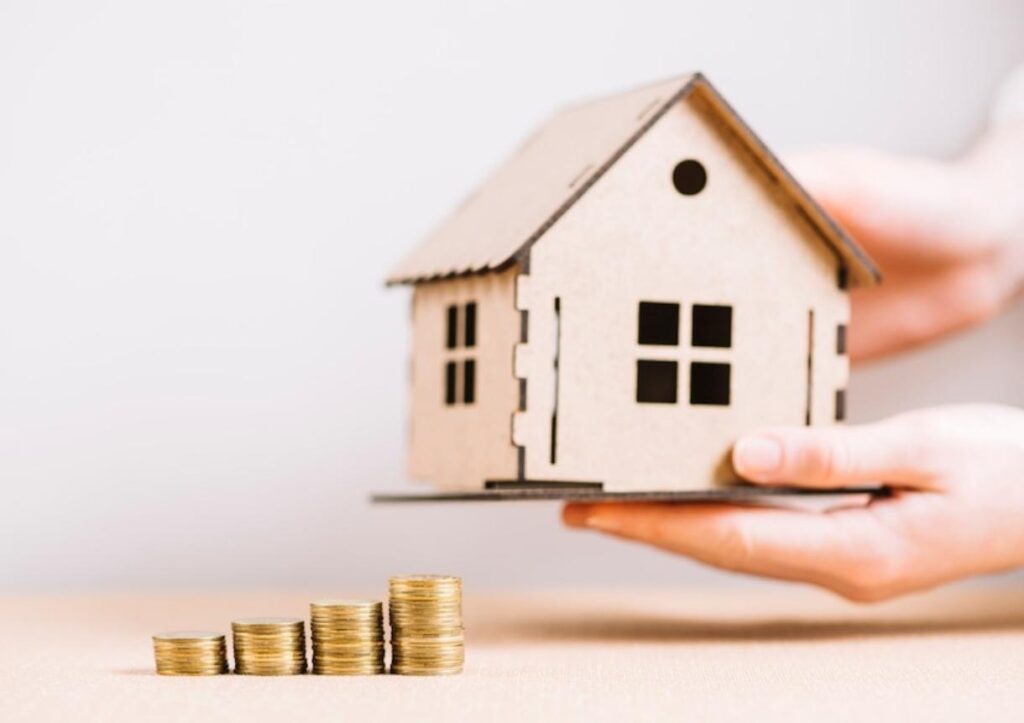 Crop hand holding house near coins