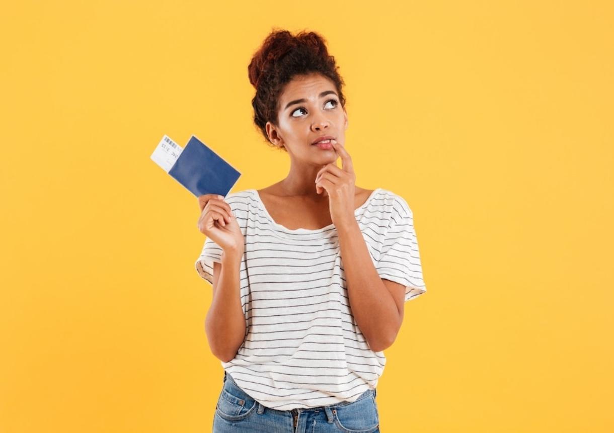 Thoghtful woman holding international passport isolated over yellow