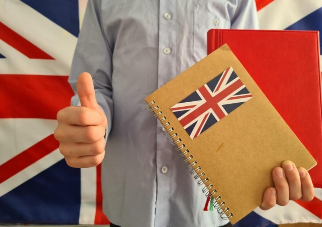 Boy holds thumb on background of uk flag