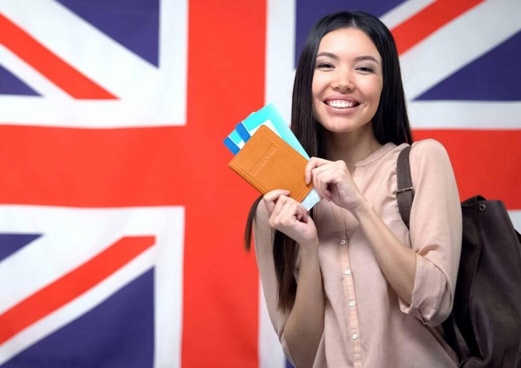 female traveler holding passport with flight tickets against British flag