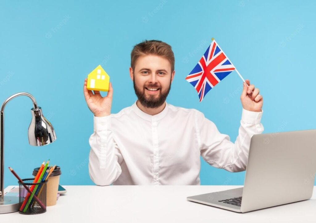 man sitting at workplace with laptop holding great britain flag