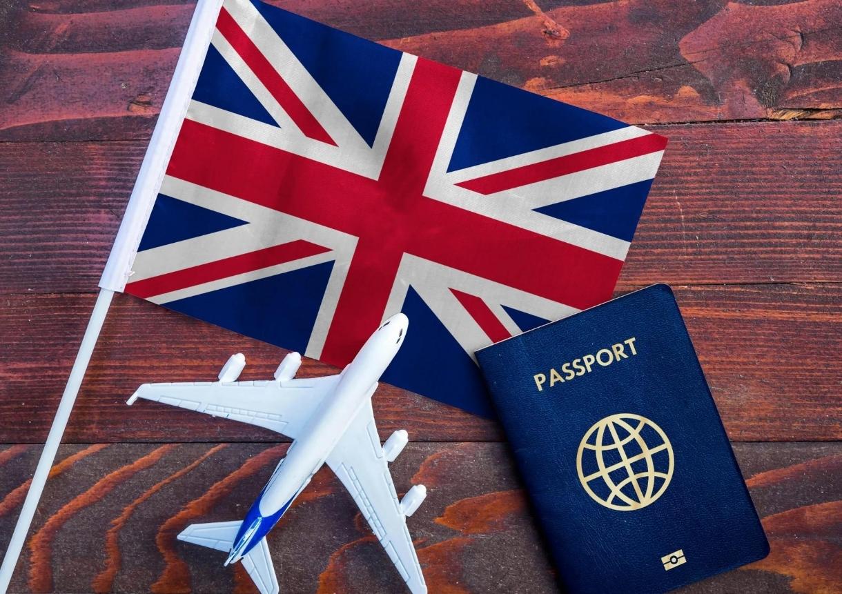 Flag of United Kingdom with passport and toy airplane
