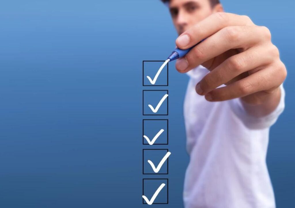 Young man checking 5 boxes with list of options on blue background