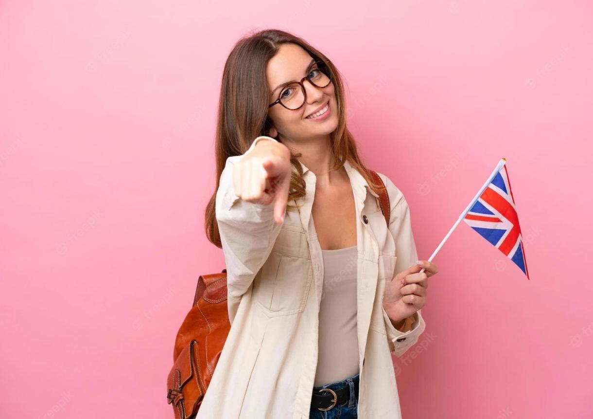 woman holding an united kingdom flag isolated on pink background